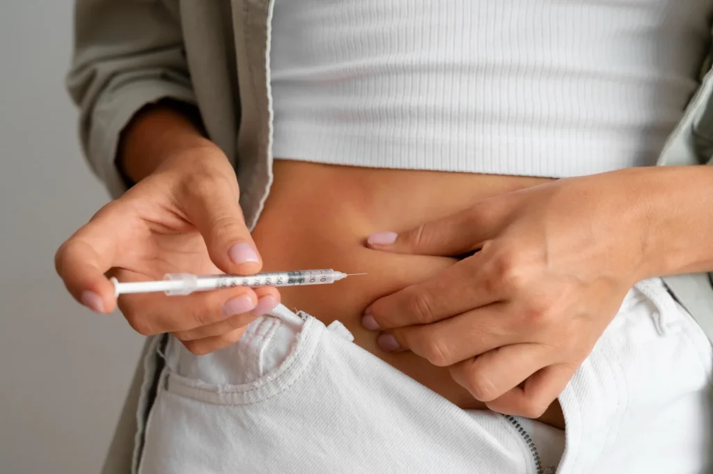 Person injecting GLP-1 weight loss drug into abdomen, representing older injectable options compared to new pills.