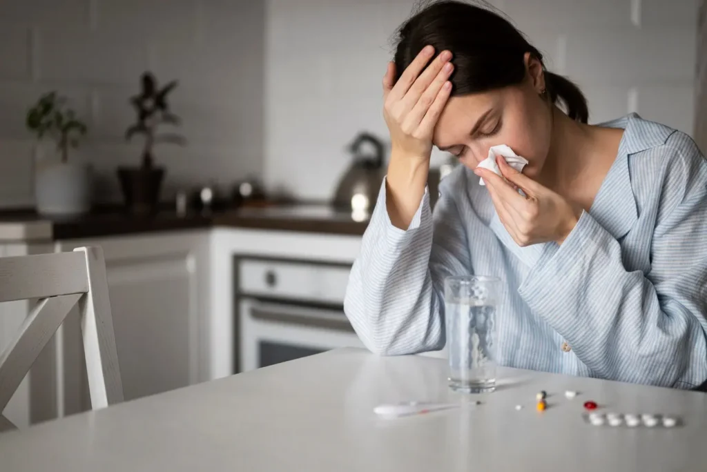 Woman experiencing possible side effects of GLP-1 weight loss pills, sitting with medication and water glass.
