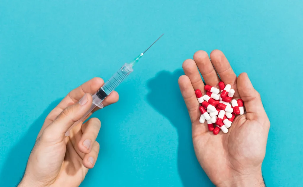 Comparison of GLP-1 weight loss pills versus syringe injection, showing capsules in one hand and needle in the other.